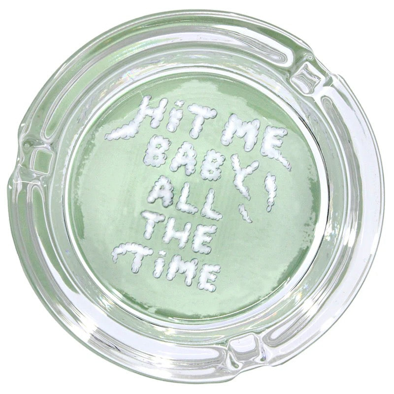 glass astray with hit me baby all the time written on white backround