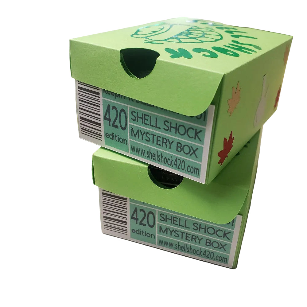 Two green 'Shell Shock Mystery Box' packaging on a surface with a blurred background.