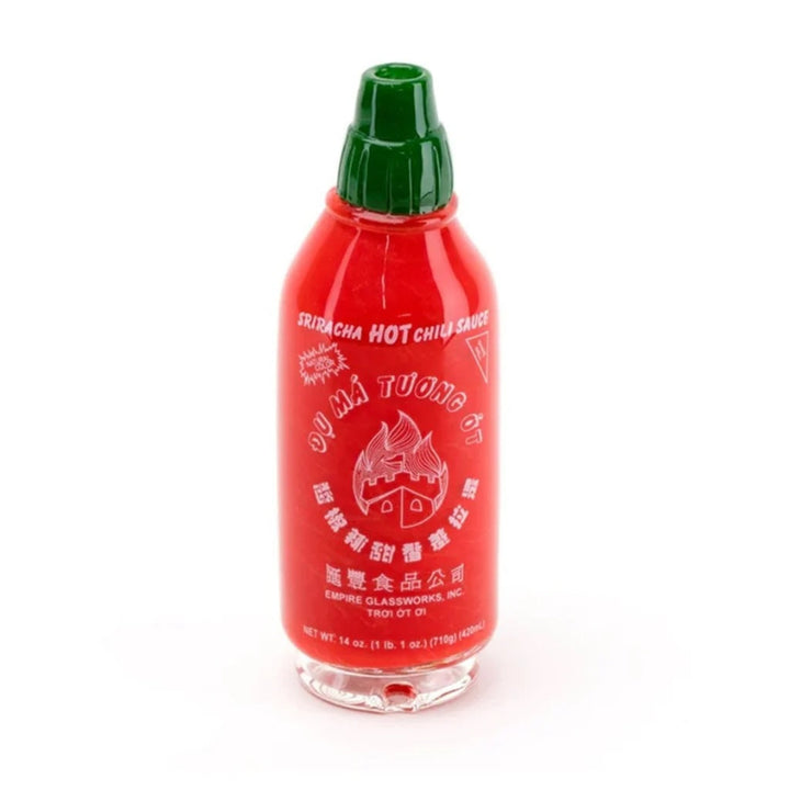 a glass, bright red sriracha bottle on a white background