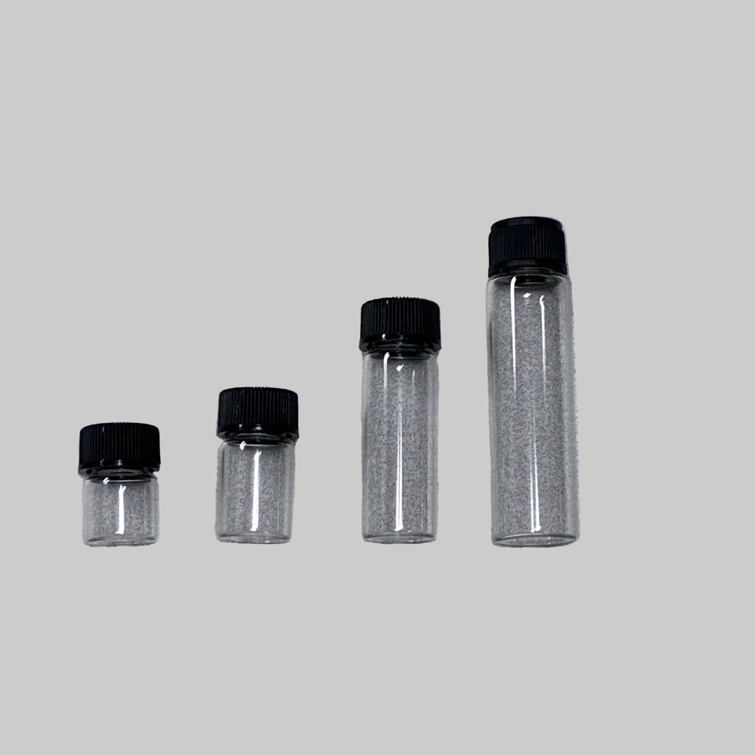 Four clear glass vials with black lids on a gray background