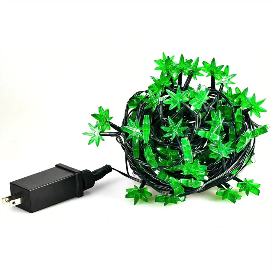 Green string lights with marijuana leaf-shaped bulbs and a black power adapter on a white background