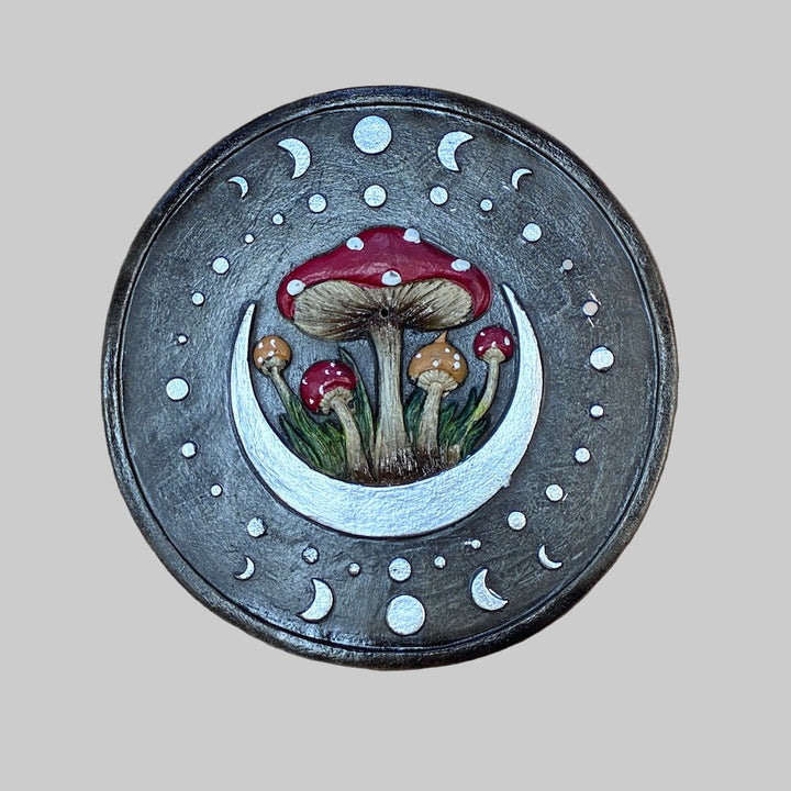 Decorative incense burner with mushrooms and celestial design on a wooden surface