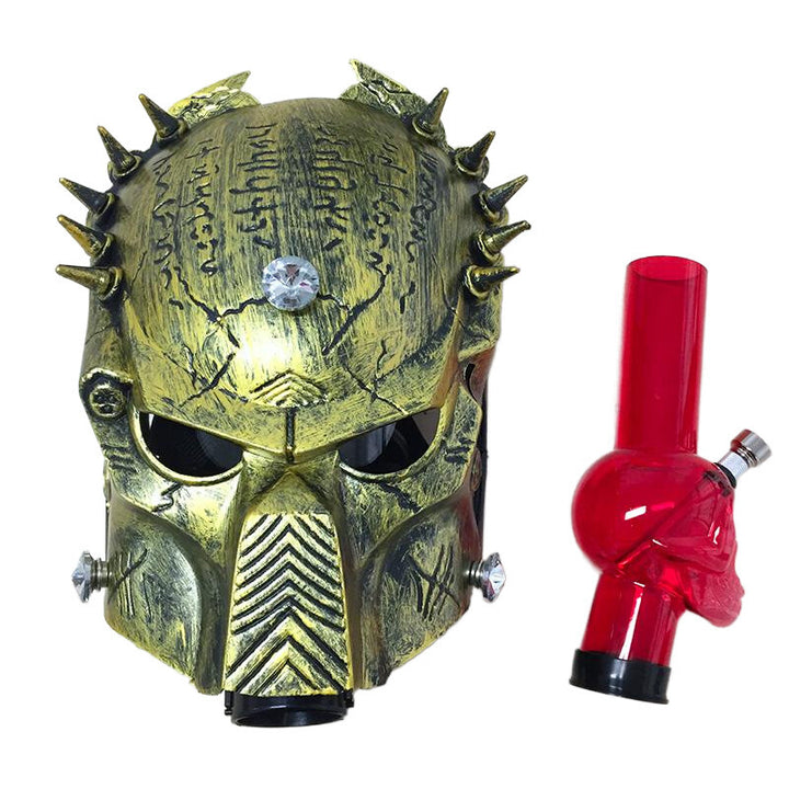 Gold predator mask with spikes and a red acrylic water pipe on a white background