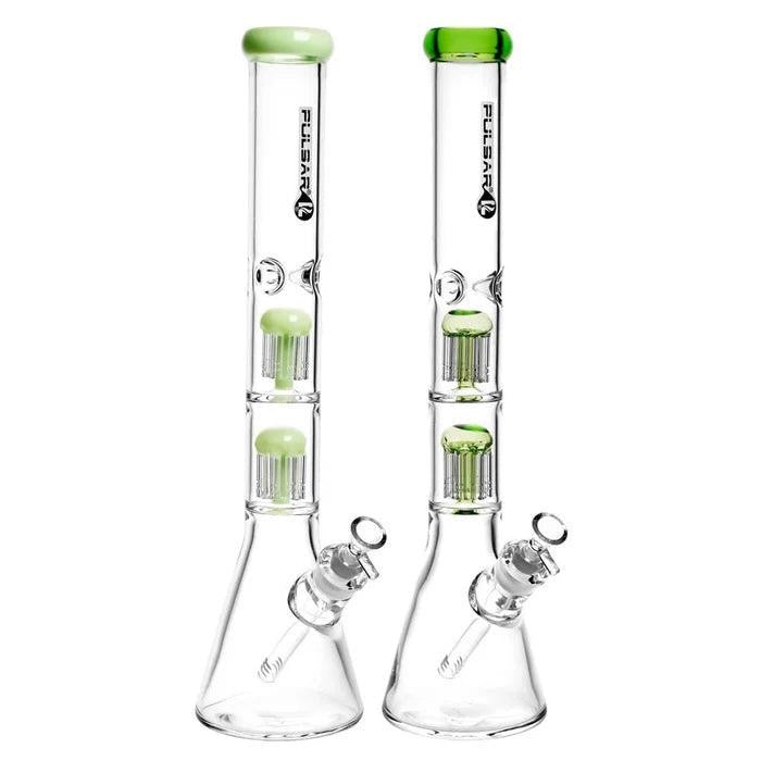 Two glass smoking devices with green tops on a white background
