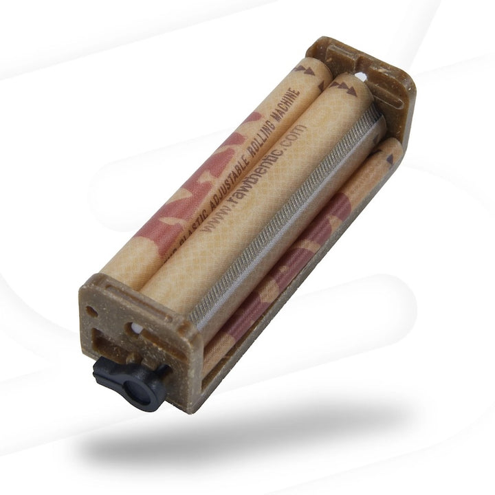 A vintage manual cigarette rolling machine with a brown plastic body, featuring two wooden rolling cylinders with red and white camouflage patterns and a black plastic toggle switch.