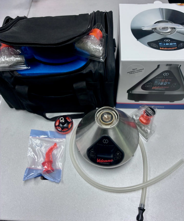 Collection of vaporizer parts including a black bag, bowl, tubing, and packaging on a white surface.