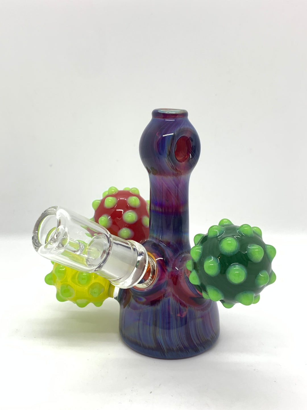 A small dab purple dab rig with a glass nail and dome. The dab rig has round decals with bumps on them, in the colours red, green and yellow. The top of the rig by the mouthpiece has a loop for you to put a chain through and wear this rig as a pendant. 